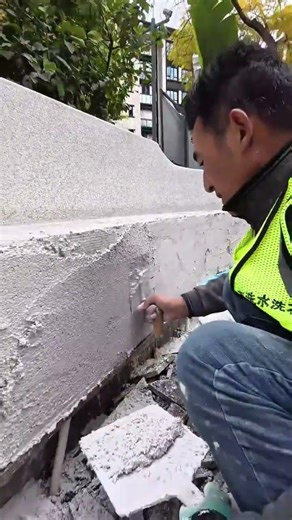 Applying pebble wash plaster and smoothing the surface onto a curved outdoor wall