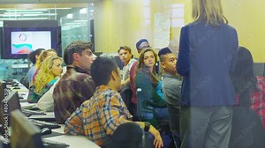 Female teacher teaching group of college students in a computer class