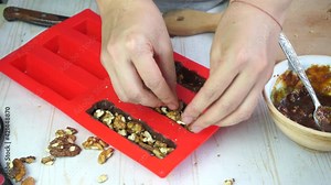 making homemade chocolate bars with nuts and caramel in silicone mold