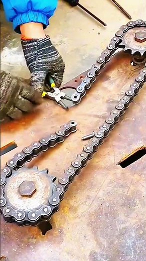 Gloved hands adjusting chain link with pliers