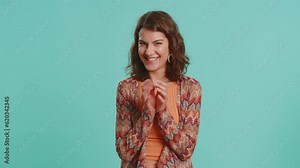 Sneaky cunning young Caucasian woman with tricky face gesticulating and scheming evil plan, thinking over devious villain idea, cunning cheats, jokes, pranks. Girl isolated on blue studio background