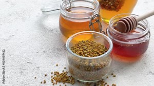 Raw organic bee pollen and honey in jars.