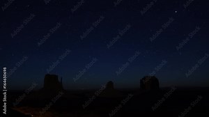 NIGHT SKY TIME LAPSE: Amazing starry night at Monument Valley landmark in Utah USA. Millions of stars and galaxies rotating above mesa mountains on clear sky. Stars, meteors, shooting stars and jets