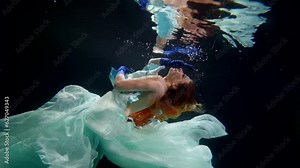gorgeous redhead woman floating in mysterious depth of magical sea, underwater shot