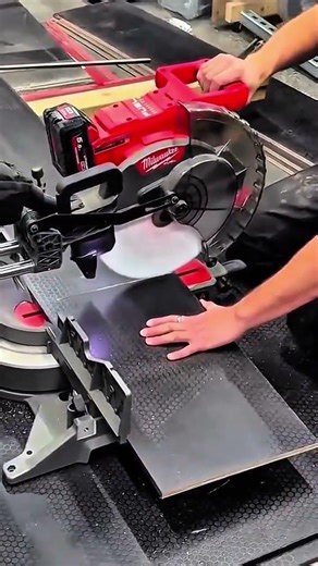 Saw blade lowers black tile steadies cut slices clean edge gleams