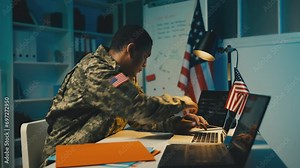 U.S. military officer working on laptop in office, planning mission strategy