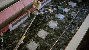 4K Electroplating process in progress, industrial tank with metal parts submerged for surface treatment, manufacturing technology, metal finishing, sustainable heavy industry practices