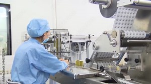 Production assembly line packaging medicine factory production pharmaceuticals and drugs, large number of capsules white tablets on the conveyor. Workers on production line in pharmaceutical cosmetics