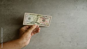Hand holding american fifty-dollar bill against a concrete background, highlighting the concept of currency and finance in the united states.