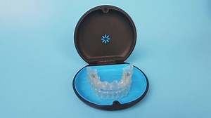 Invisalign braces or invisible transparent aligner on blue background front view.