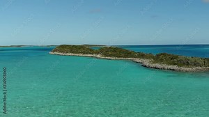 Drone pans over crystal clear water and small islands in the Caribbean Sea, located in the islands of the Exumas, Bahamas. Gently flowing water shown from an aerial view via Mavic Air.