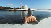 A man swiming in an ice hole in winter. Winter swimming is a...