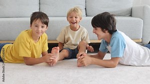Happy positive children, tickling on the feet, having fun together, boy brothers at home having wonderful day of joy together