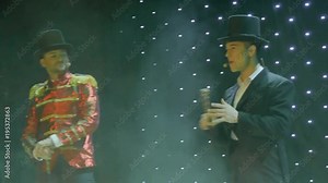 Stylish man in tail-coat singing on the stage in theatre