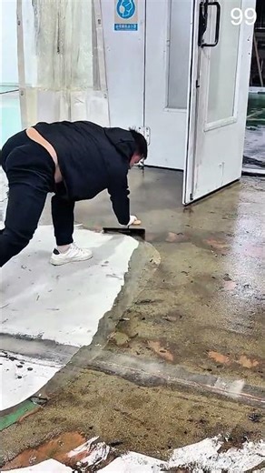 Worker applying white coating across industrial workshop floor