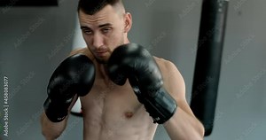 Kickboxer in boxing gloves does shadow boxing and trains at boxing club, fighter man is fighting with shadow, kickboxer training strikes in gym, 4k 60p Prores HQ