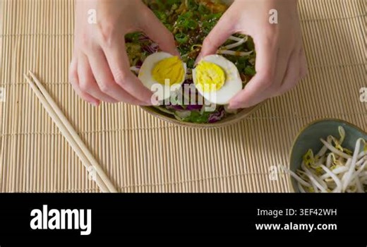 African American woman wearing mint bangle placing egg halves on salad for serving on bamboo mat. Plating, overhead, greens, sprouts, sesame, halves, hands Stock Video Footage - Alamy