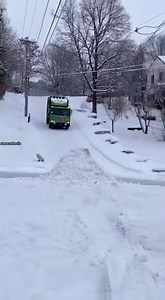 Garbage Truck Goes Airborne on Icy Hill, Debris Covers Front Lawn 🗑️❄️ Traverse City, Michigan — Wednesday, March 19, 2025 Vertical smartphone footage shows a large green garbage truck descending a steep residential street during snowy conditions when it strikes a snow-packed ramp at an intersection. The truck lifts into the air before slamming back down onto the roadway. The force of the landing bursts open the rear compactor door, sending hundreds of black trash bags and loose debris spraying
