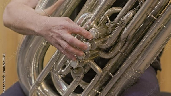 Musician is playing a tuba and pressing the valves