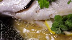 Cooking bream fish in a pan with oil, lemon and parsley. Mediterranean kitchen, healthy. Restaurant.
