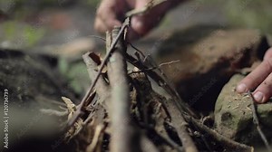 Detail of a male camper arranging sticks for a campfire in slow motion.