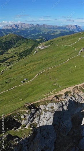 Vertical screen Ridge Edge Seceda Dolomites Italy Dramatic Viewpoint Over Steep Escarpment And Winding Trails Foreground Cliff Dropping Into Shadowed Chasm Quiet Contemplative Mood Ideal For Hiking