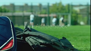 Kids throwing their backpacks on the grass ground and running to play football after school lessons . Close up many bags or schoolbags on the floor . Children playing soccer on background in sunny day