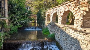A mountain river flows through a cascade channel, surrounded by lush greenery, stone walls, and sunlight. This footage is ideal for an intro sequence, capturing the dynamic beauty of nature