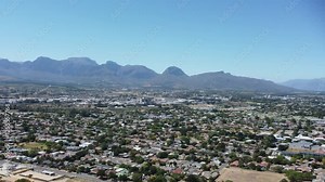 Camera panning left to right across Paarl Town South Africa with the iconic Paarl rock and the Mountain range behind the town 4K Aerial Video