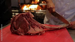 Huge T-bone meat stake, chief cleans the bone from fat before cooking. High quality FullHD footage
