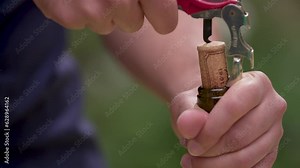 Close-up slow-motion of a person removing the cork from a wine bottle with a corkscrew