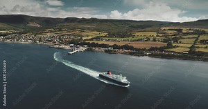 Ferry terminal, Brodick Gulf aerial view. Ship near shore with greenery lands and mountains on horizon. Magnificent seascape with water transportation of Arran Island. Footage shot in 4k, UHD