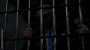 White collar criminal in dark dingy jail cell