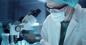 Female Lab Scientist in Mask Using Microscope