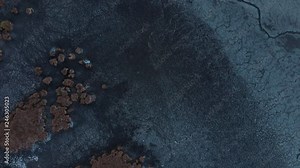 Top down aerial view of Bavarian lake in winter, the lake bed dried out and frozen, cracked slabs of mud covering the surface. Bavarian lakes are an important source for water, now struck by drought