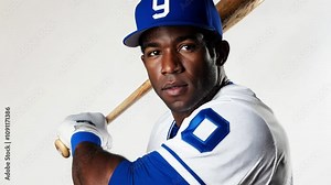Player in a blue baseball cap and jersey poses with a bat, showcasing determination and readiness for the game