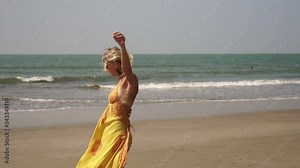 Beautiful young woman is dancing on the sea beach. Girl dance on the beach