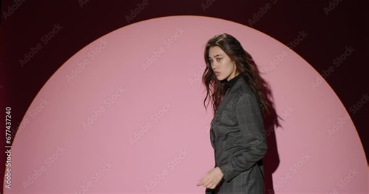 Backstage professional fashion photo shoot. Slow motion. Young attractive relaxedness confident girl model poses in light of white cyclorama for photographer. Photo session of relaxed confident gait