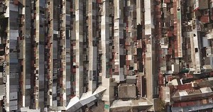 Aerial top-down view high altitude of slum a heavily populated urban informal settlement characterized by substandard housing and squalor poor living conditions streets and rusty metal home roof tops