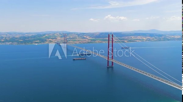 Lapseki, Turkey. 1915 Canakkale Bridge with moving cars above and multiple cargo ships and a passenger ferry on the Dardanelles below. Aerial View