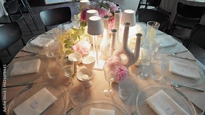 Dining table set for an event with multiple place settings, glassware, and a floral centerpiece.