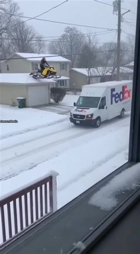 Snowmobile Falls From Roof, Crashes Into FedEx Van Below ❄️🚐 Duluth, Minnesota — Sunday, March 16, 2025 Smartphone footage filmed from a second-story window shows a yellow snowmobile already airborne after launching off a rooftop. The machine slams onto the hood of a moving FedEx delivery van traveling along the street below. The rider is thrown clear, but the throttle remains engaged, causing the track to spin violently against the metal hood and spray plastic fragments and sparks. The van swe