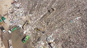 Aerial top view of A Huge Waste, garbage, dump, rubbish landfill. A landfill compactor, group of workers sort out the garbage in the landfill. Trash trucks dump waste polluting products.