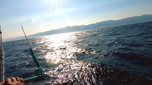 Kite surfing competition in amazing sea sunset, professional male surfer holding his yellow professional kite and riding on water doing different sport maneuvers. Competitive sport on water