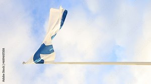 Video of Finnish flag blue cross on a white field flying on a flagpole against a blue sky with sun and clouds