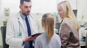 Cute Little Girl Visits Friendly Doctor with Her Mother. Doctor Talks with them and Uses Digital Tablet Computer. Healthy Child and Modern Health Care Service.