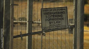 White sign with words state of California, trespassing loitering forbidden by law, section California penal code