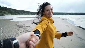 Woman holding man hand smile on beach. Female leading a man forward to the adventure. Follow me concept. Slow motion