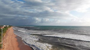 An aerial view of the Atlantic Ocean off Boynton Beach, Florida on a cloudy day. The camera starts low over the sand then dolly in and boom up over the white waves, a day after hurricane Milton.