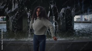 A woman expressing her energy through dance near a flowing waterfall in a natural outdoor setting